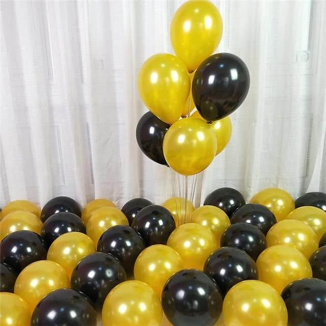 Black and gold balloons for party decoration, featuring a cluster of gold and black balloons on a floor covered with more balloons.