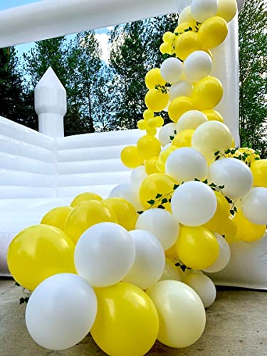 Yellow and white balloons decoratively arranged near a bouncy castle for festive celebrations.